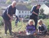 Photograph of two women working on an allotment plot with their children