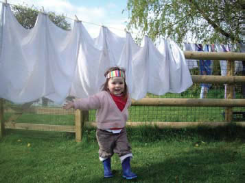 Photograph of a girl playing in front of a washing line