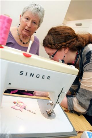 Picture of a lady looking over a sewing machine taken at the 2011 Clothes Swop