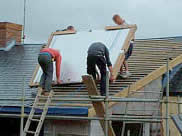 Photograph of men installing solar thermal panels on a roof