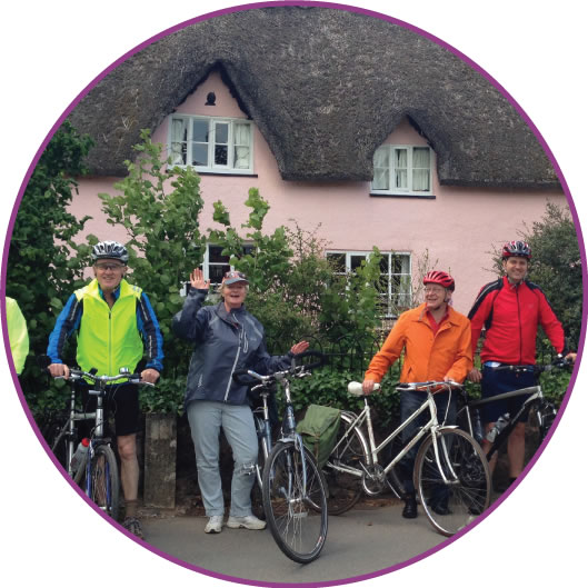 Picture of a group of cyclists outside a thatched cottage