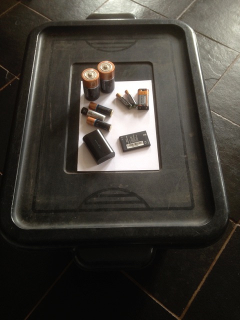 Photograph of a black recycling box with batteries