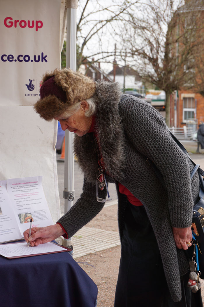 Photograph of a woman signing the Food Group petition against supermarket food waste